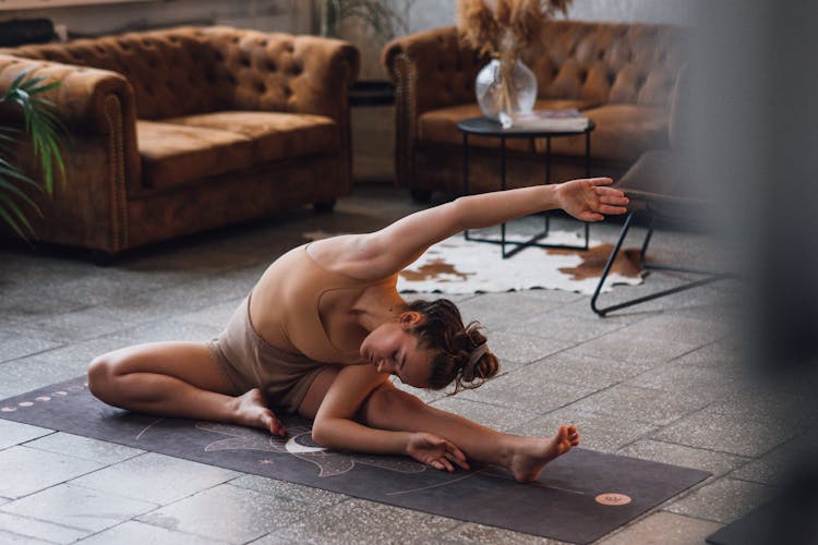 Photo Of A Woman Stretching Her Arm On A Black Yoga Mat