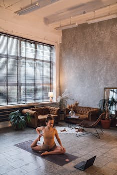 A woman performing yoga poses in a stylish, cozy living room setting with natural lighting and plants.