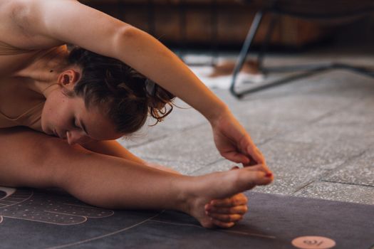 Woman stretching on a yoga mat indoors, showcasing flexibility and focus.