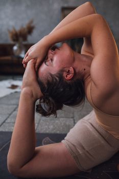 Close-up of a woman doing a yoga pose on a mat indoors, focused on flexibility and wellness.