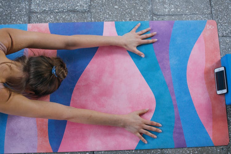 Overhead Shot Of A Woman Doing Yoga Near A Cell Phone