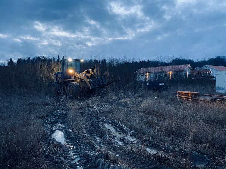 Blue Image Of A Tractor On Field In Dusk And Overcast