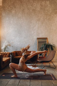 Woman performing a yoga pose in a cozy indoor setting with armchairs and plants.