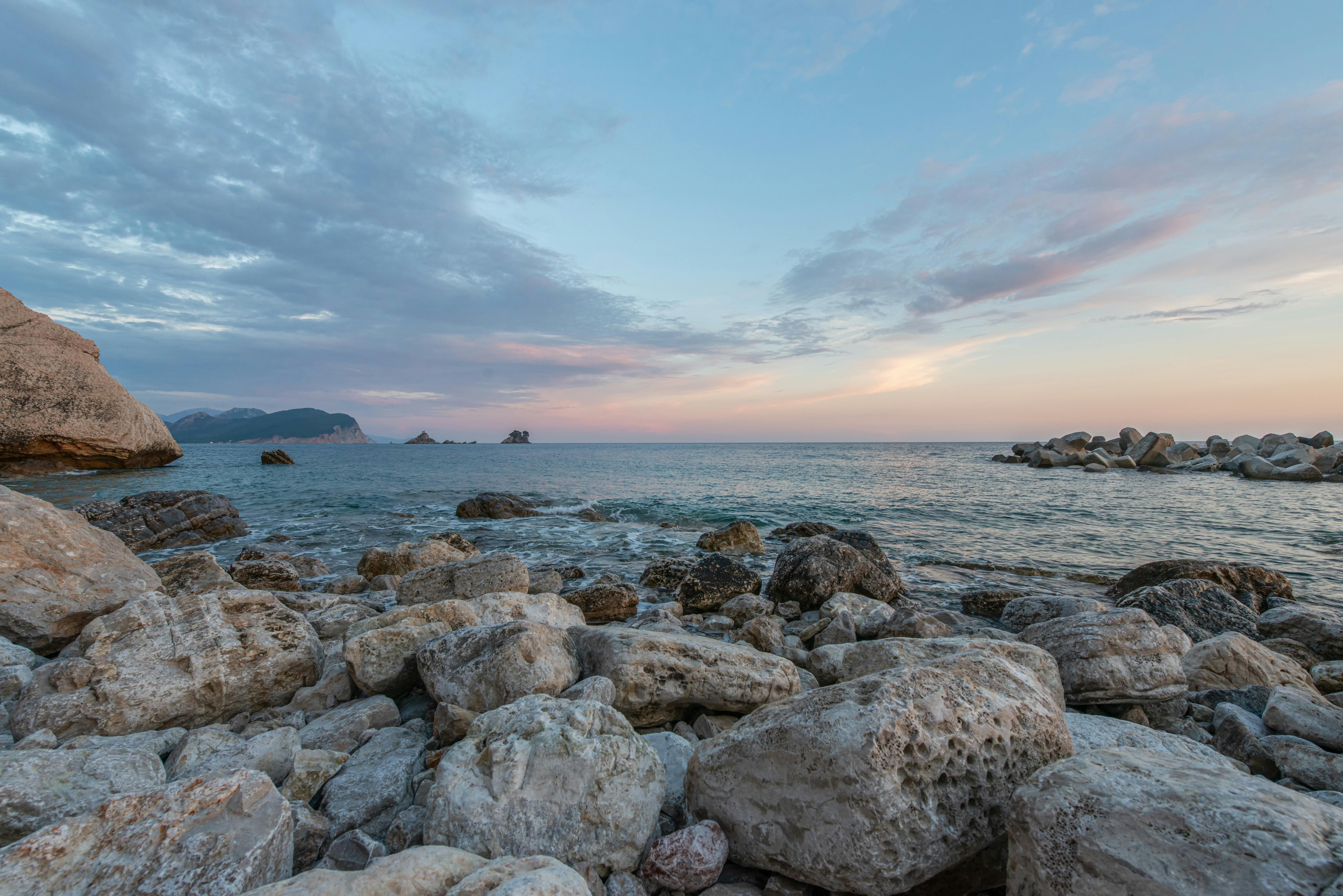 vast water of rippling ocean with stony coast