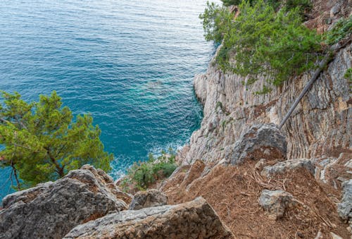 Montaña Rocosa Marrón Junto Al Mar Azul