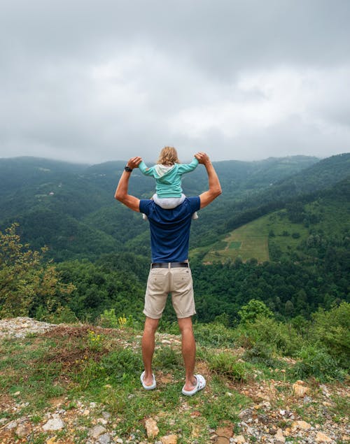 Unrecognizable man with child on hilltop