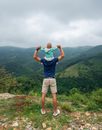 Unrecognizable man with child on hilltop