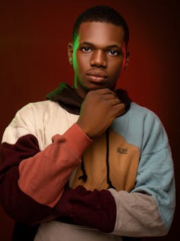 Studio portrait of a young man in a colorful hoodie with a serious expression.