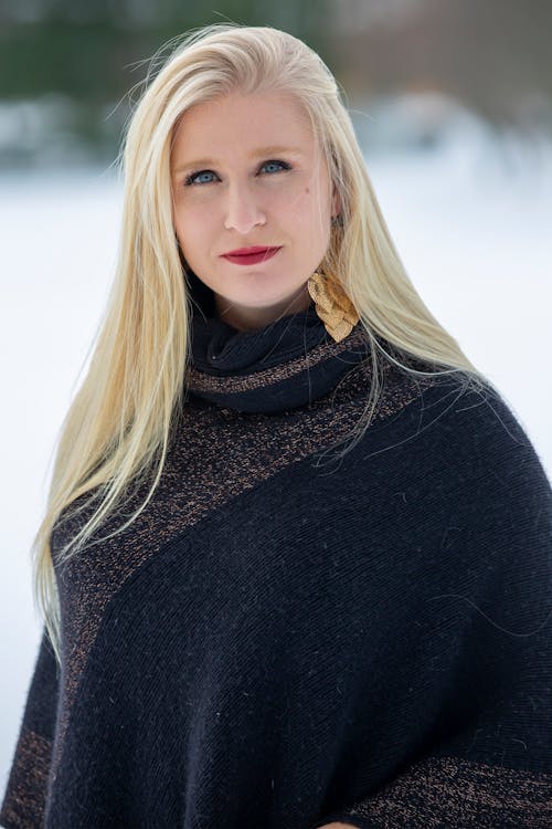 Calm woman in sweater standing in winter forest