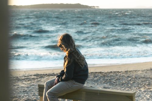 Free Woman on a bench at Punta del Este beach, Uruguay, enjoying a serene sunset. Stock Photo