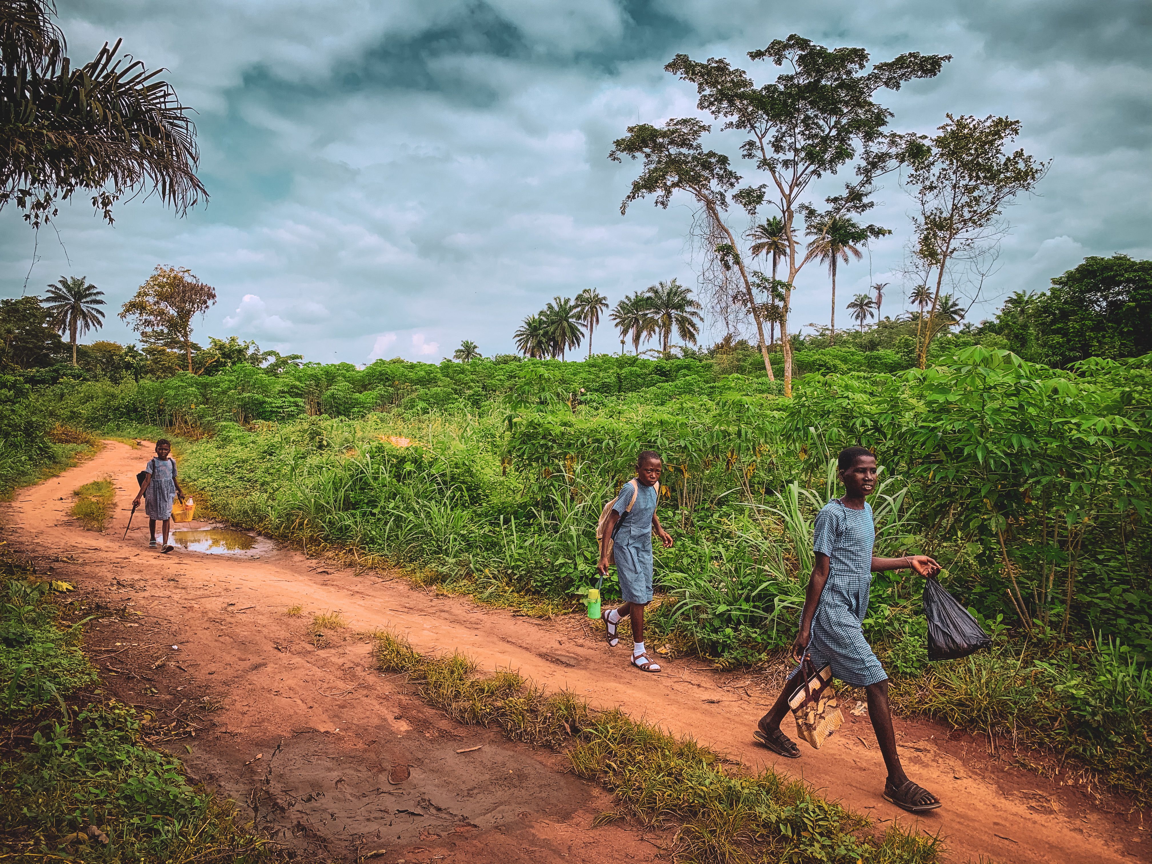 Un camino de tierra atraviesa una aldea africana bajo cielo nublado