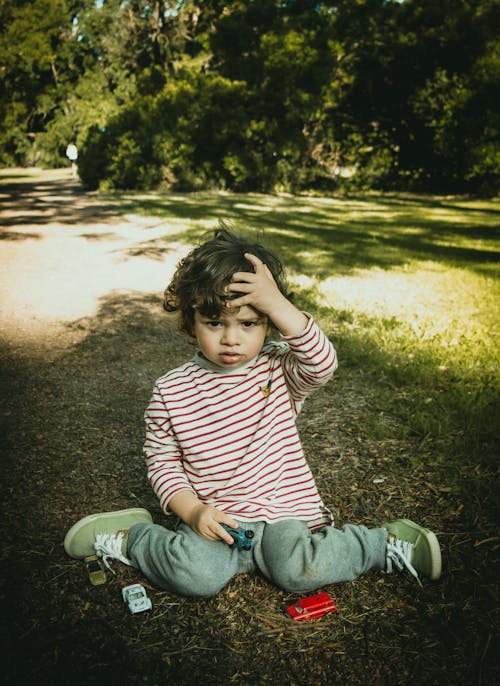 Free Young Kid Sitting on the Ground Stock Photo