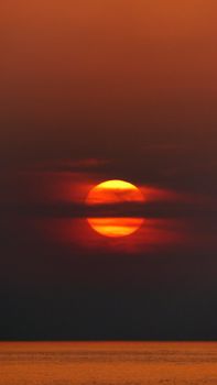 A breathtaking sunset with a dramatic sky, casting golden hues over the calm ocean waters.