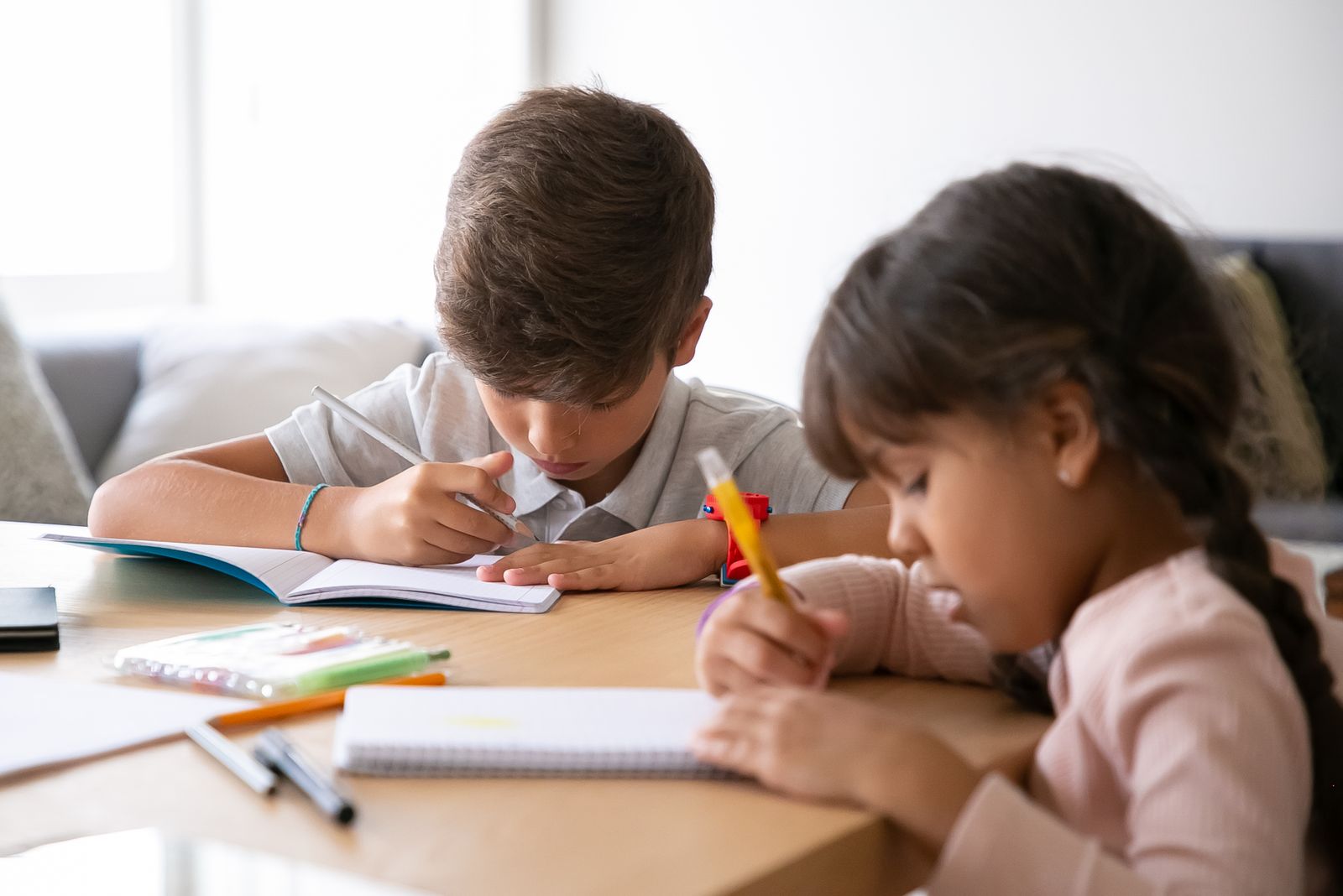 Two school-age students completing schoolwork together at home.