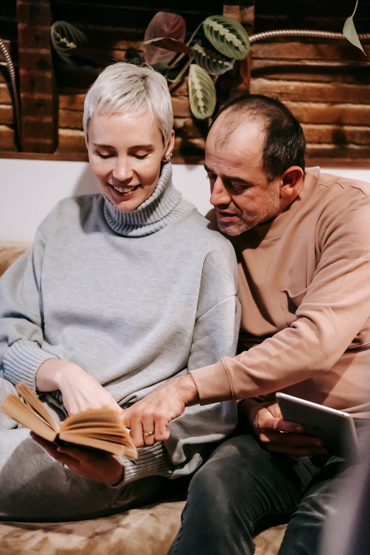 Positive Adult Diverse Couple Reading Novel On Couch