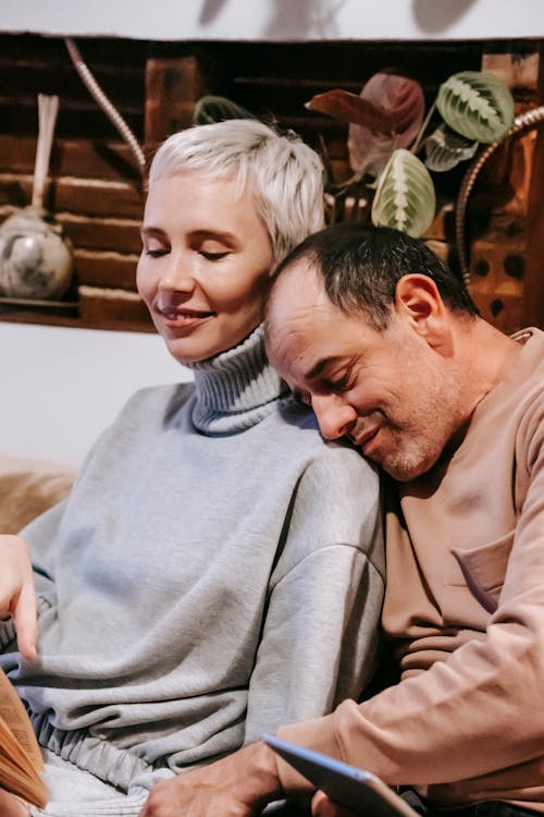 Loving middle aged diverse spouses hugging on sofa at home