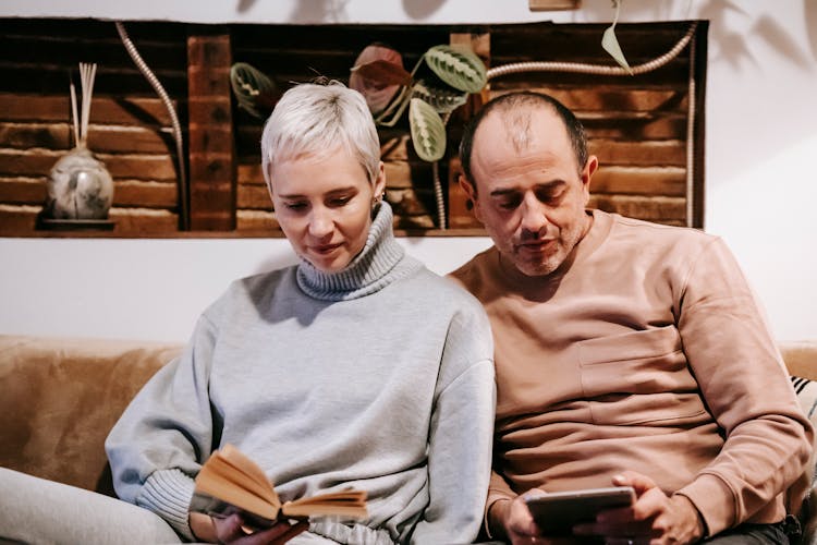 Calm Multiracial Couple Spending Weekend With Book And Tablet At Home