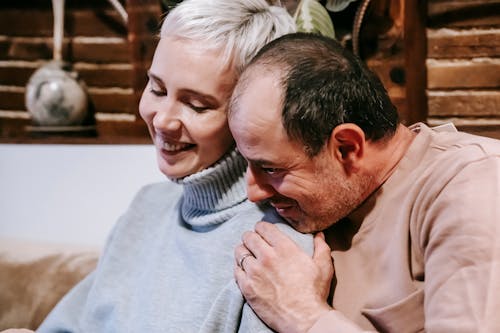 Happy multiracial couple cuddling while resting together on couch at home