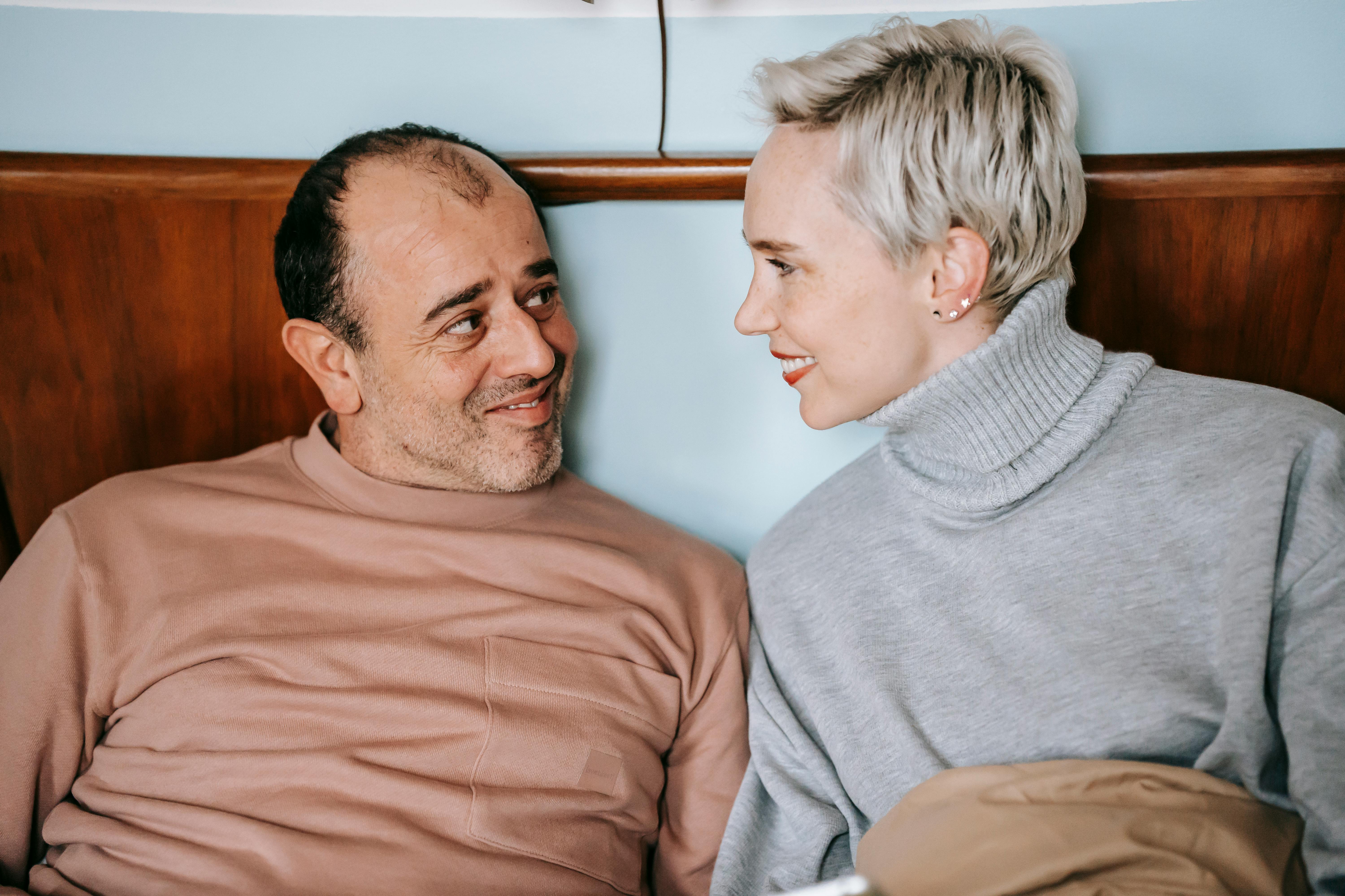 loving multiethnic spouses smiling while resting in bed in morning