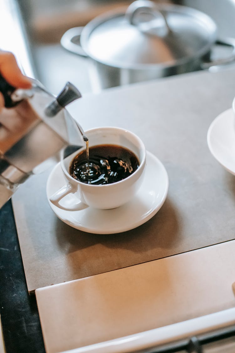 Crop Person Pouring Coffee From Maker Into Cup At Home