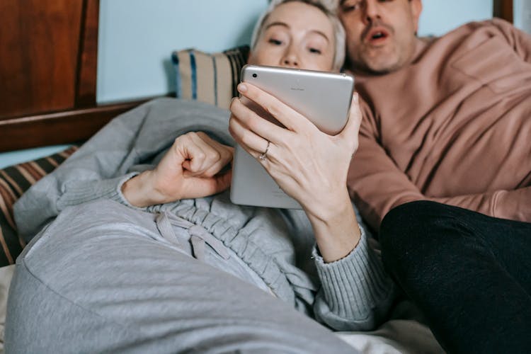 Relaxed Multiethnic Couple Lying On Bed And Watching Video On Tablet