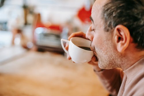 Content ethnic man drinking coffee at home