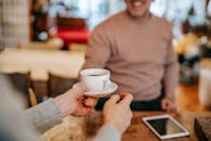 Crop couple having breakfast together with coffee at home