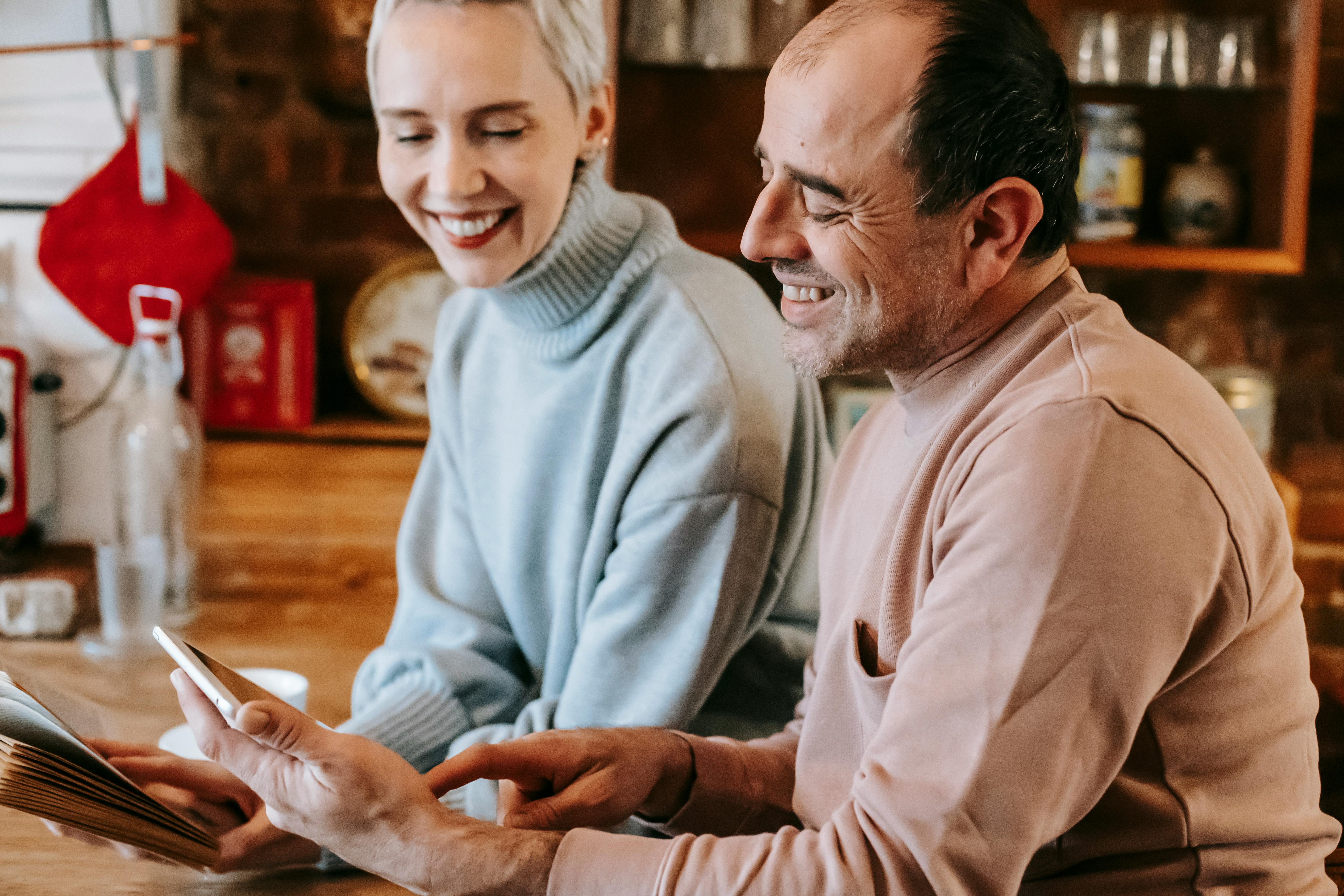 joyful diverse couple smiling and using tablet at home