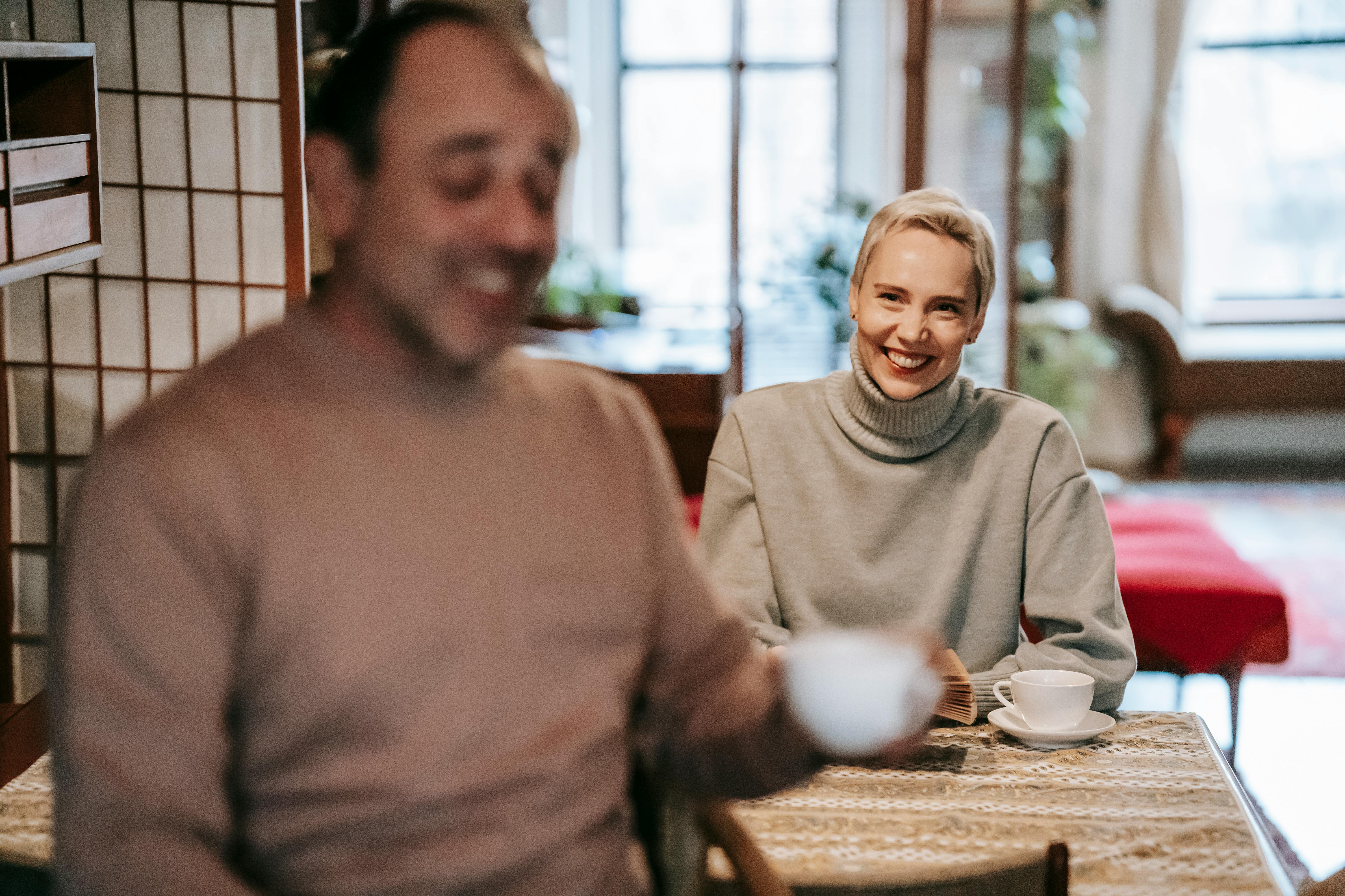 joyful adult multiracial spouses smiling and communicating during breakfast at home