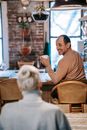 Cheerful ethnic male drinking coffee and communicating with unrecognizable wife at home