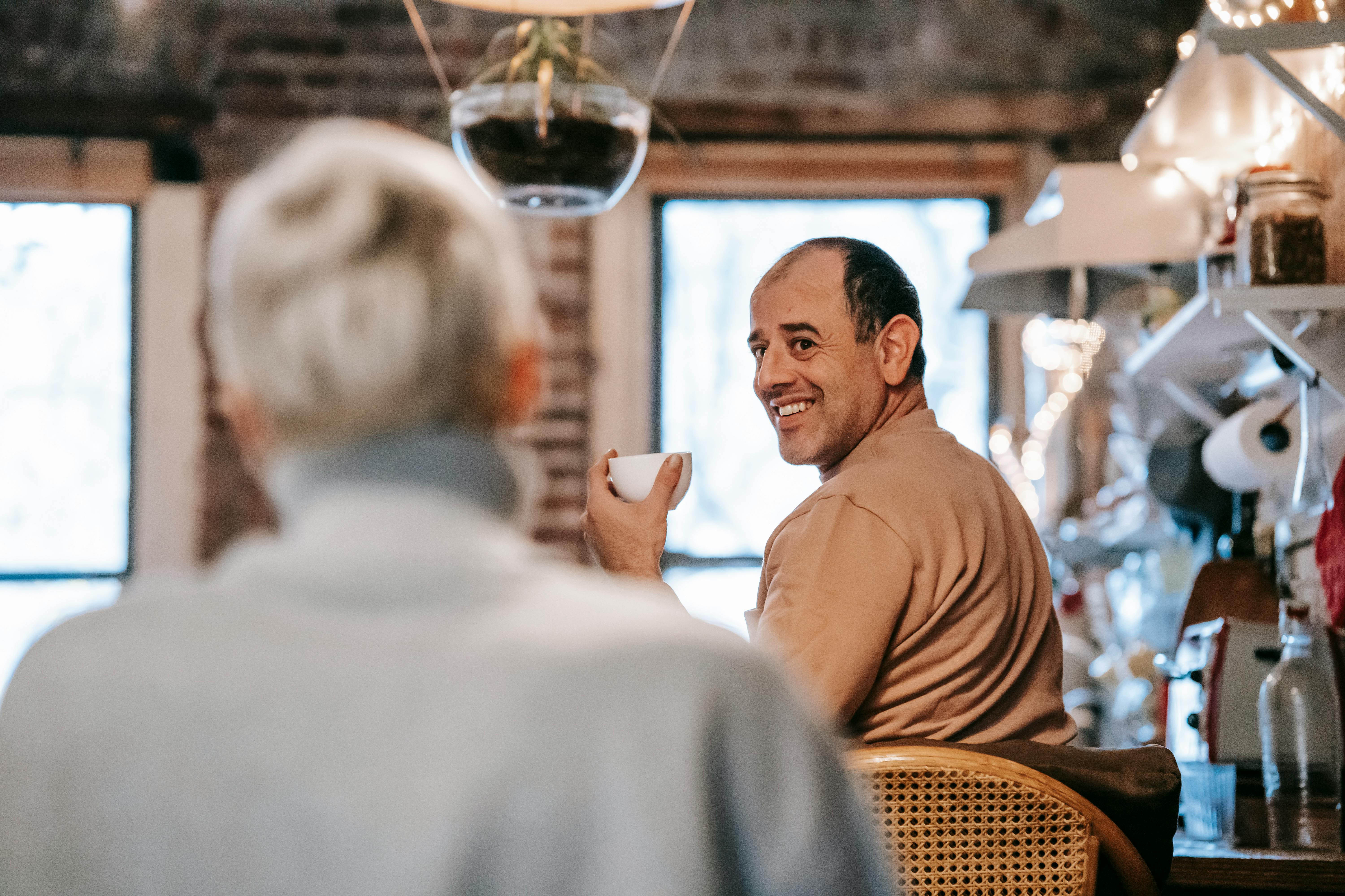 cheerful ethnic man chatting with anonymous wife during breakfast at home