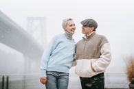 Content adult couple embracing and looking at each other against urban bridge in misty weather