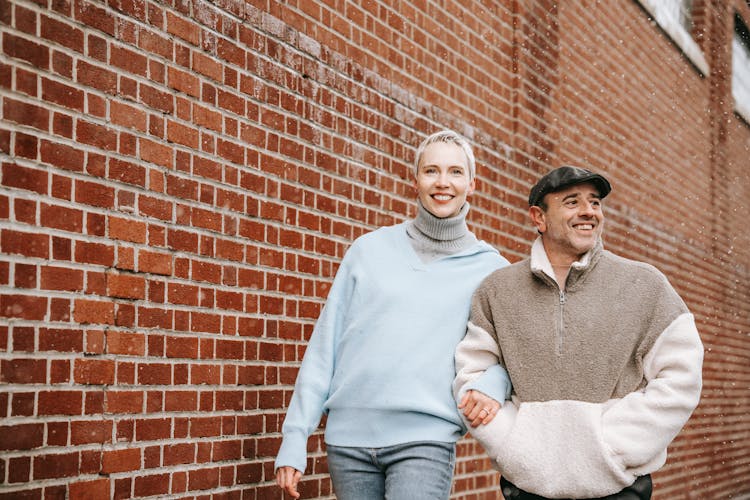 Happy Multiethnic Couple Walking Along Brick Building