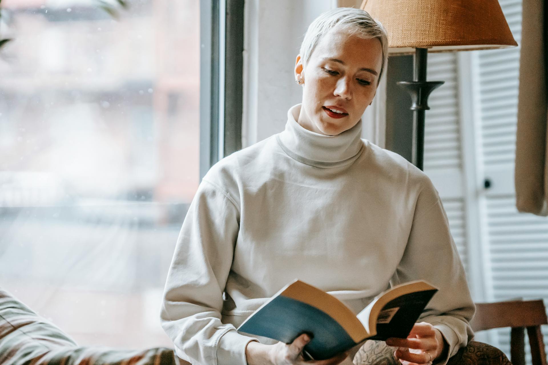 Woman reading interesting book near window