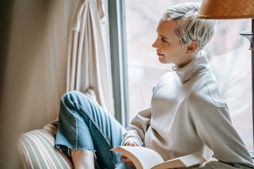 Free Content intelligent woman with book resting on window Stock Photo