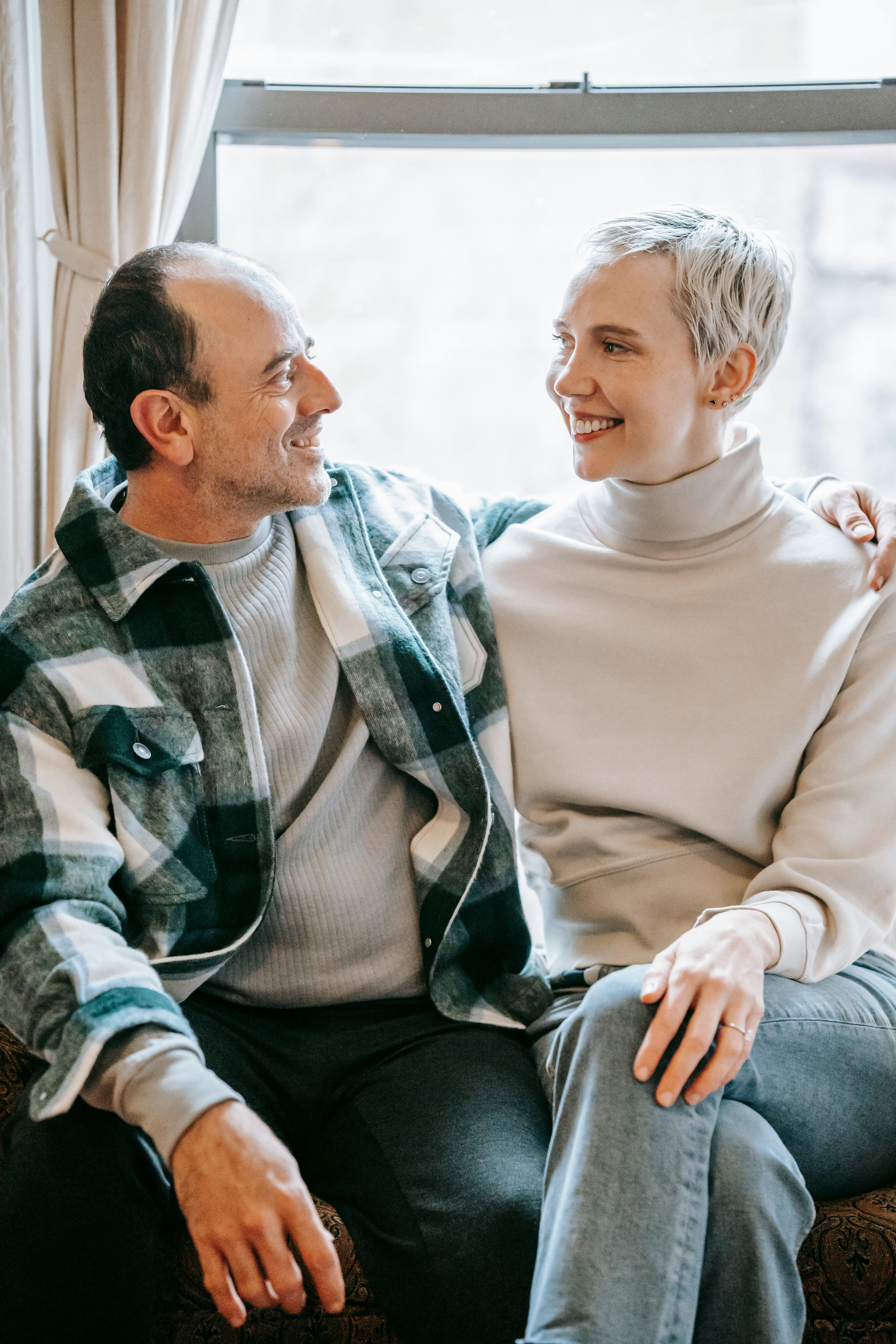 positive couple bonding and smiling on window