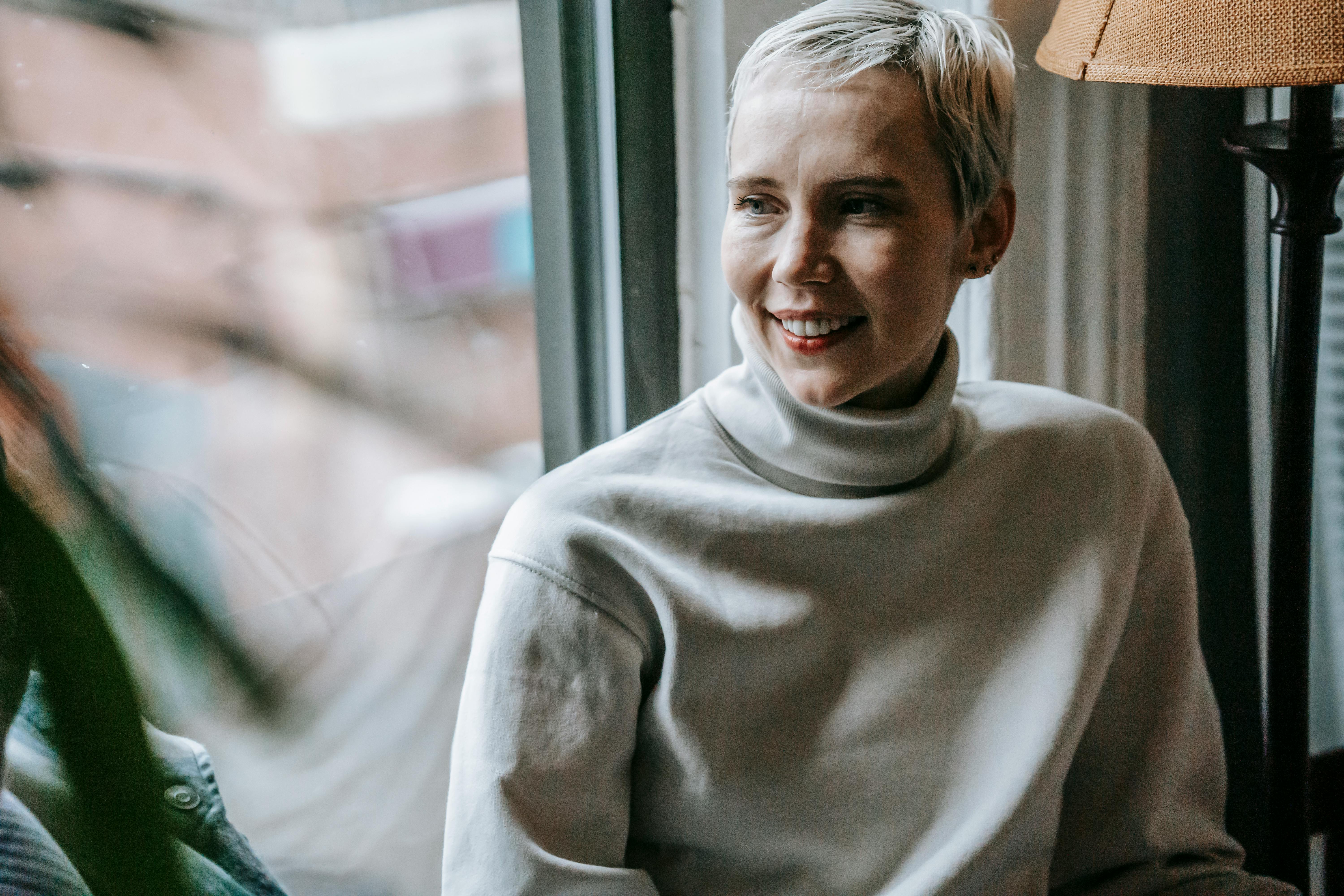 positive female near window and plant in cafe