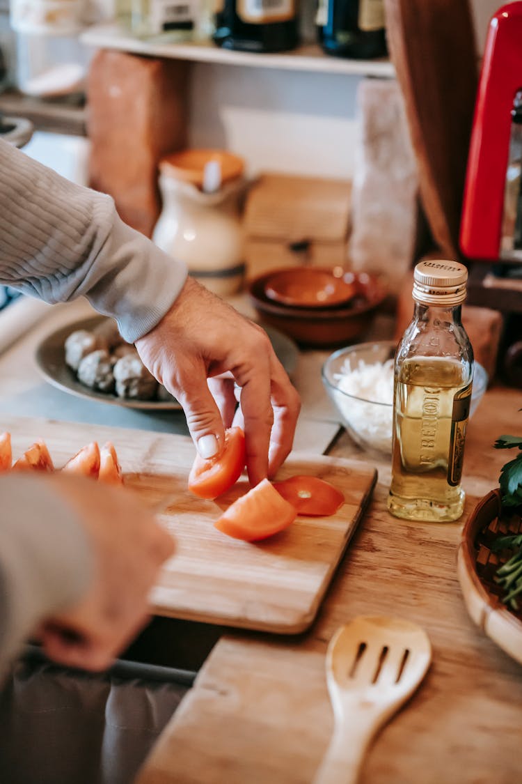 Crop Person Cutting Ripe Tomato On Chopping Board At Home