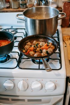 Delicious homemade meatballs cooking in a pan on a stove, showcasing culinary skills.