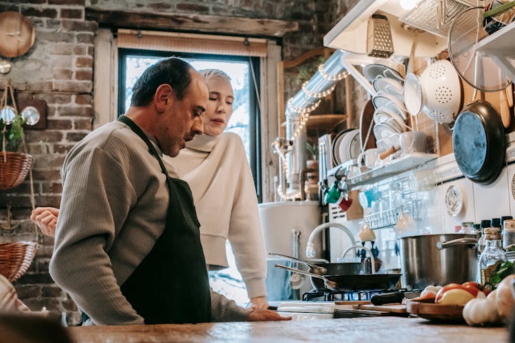 Focused Diverse Spouses Cooking In Kitchen At Home