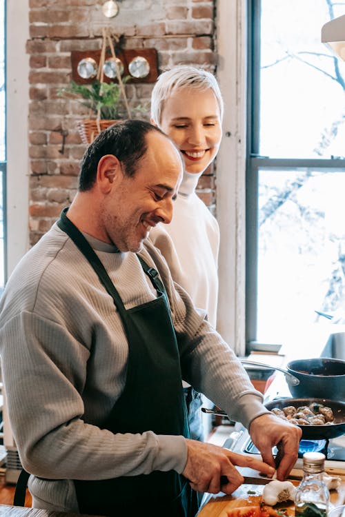 Happy multiethnic spouses cooking together in kitchen during weekend at home