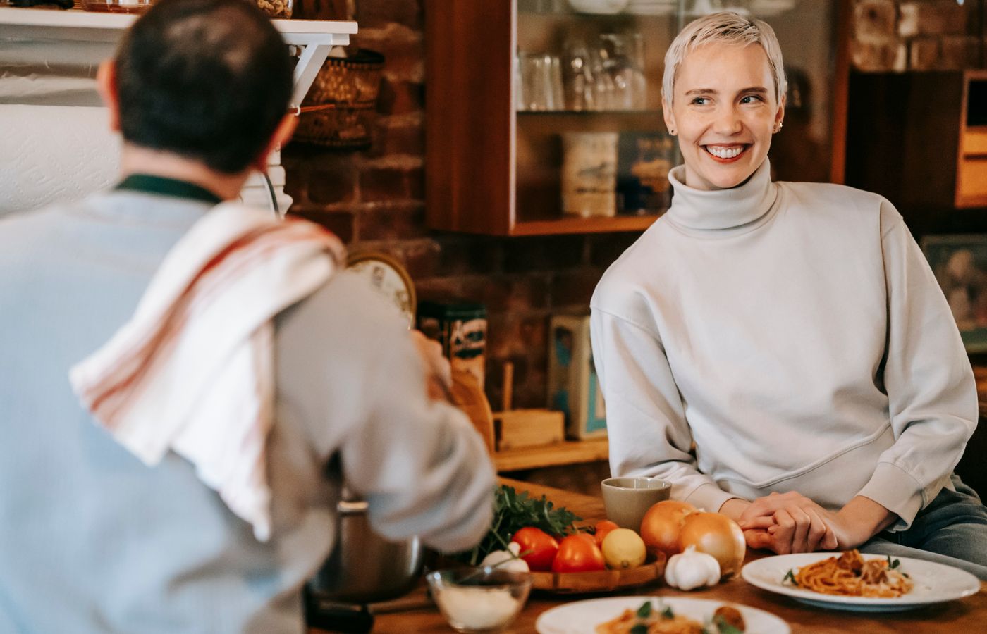 Cheerful couple preparing a meal in a warmly lit kitchen showcasing friendship and togetherness.