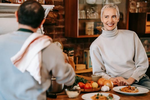 Cheerful couple preparing a meal in a warmly lit kitchen showcasing friendship and togetherness.