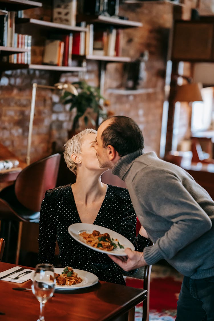 Couple Having Dinner While Kissing In Restaurant Near Pasta