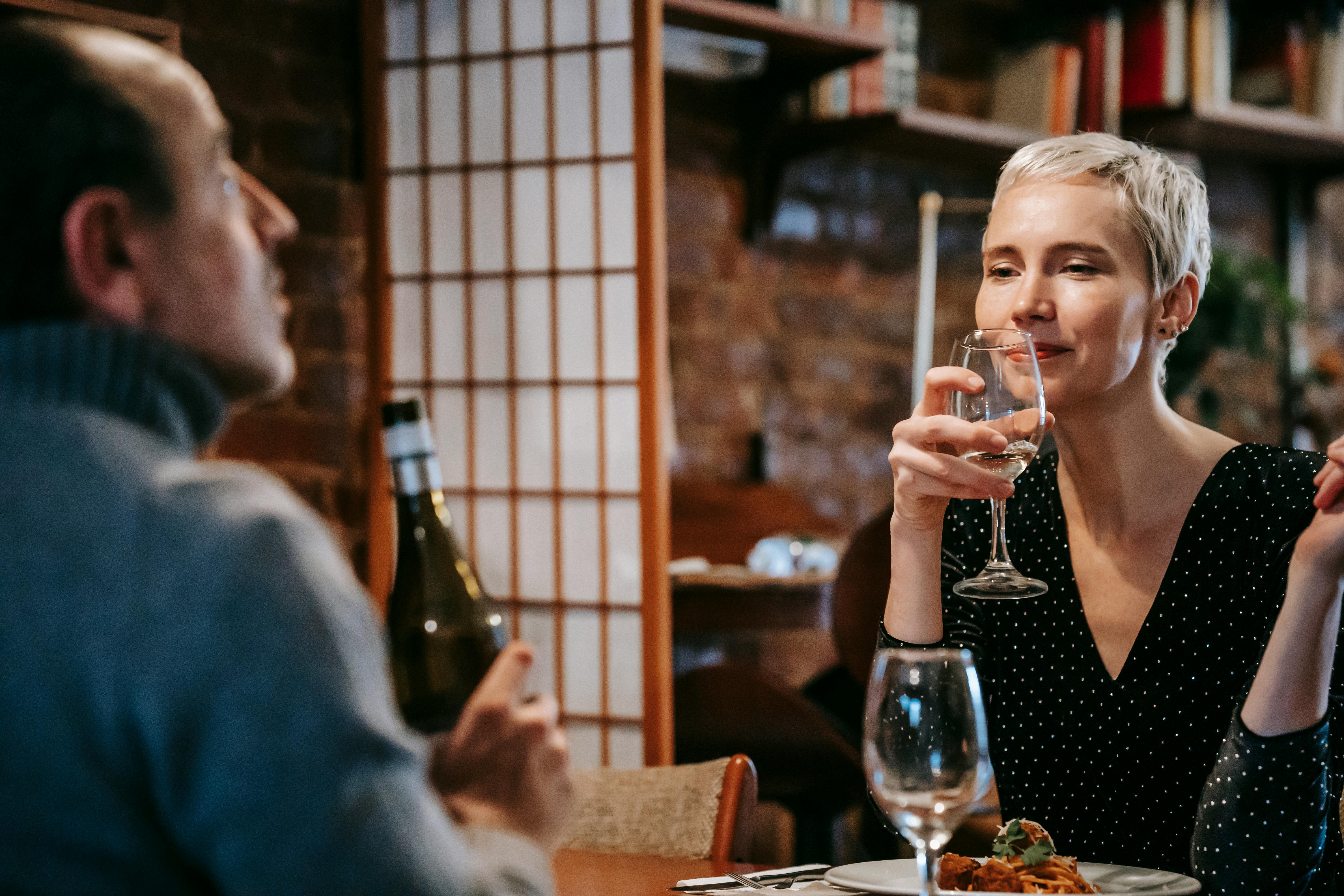 A couple enjoying a romantic dinner with wine in a cozy restaurant setting.