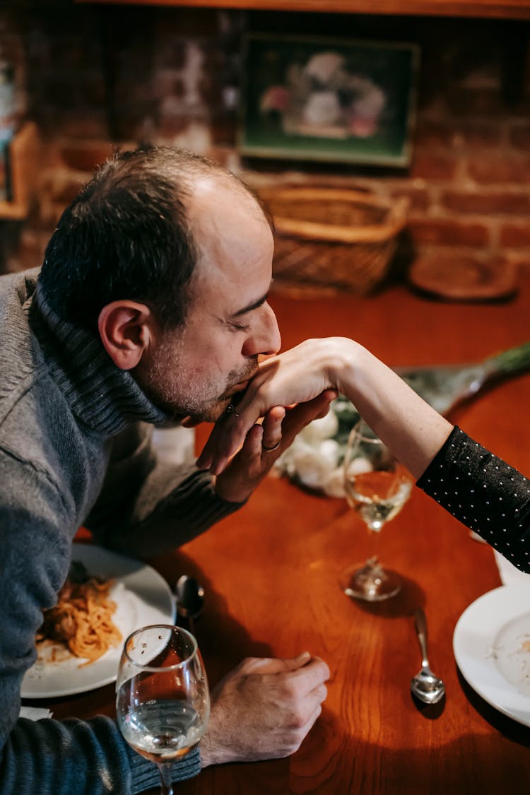 Couple Having Date While Kissing Hand In Restaurant With Food