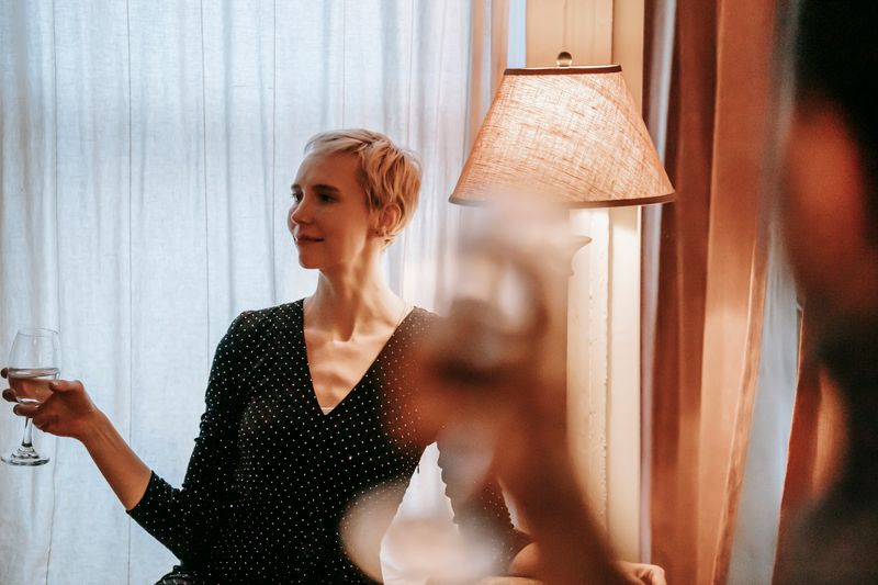 Woman in dress enjoying wine at a lamp-lit table