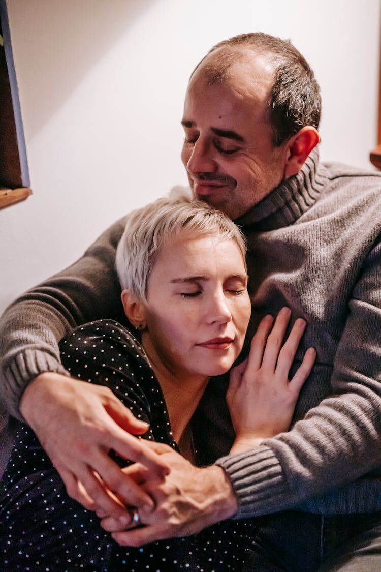 Smiling Gentle Man Embracing Wife With Closed Eyes