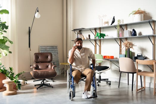Confident bearded man in wheelchair talking on phone in stylish office with shelving and plants.