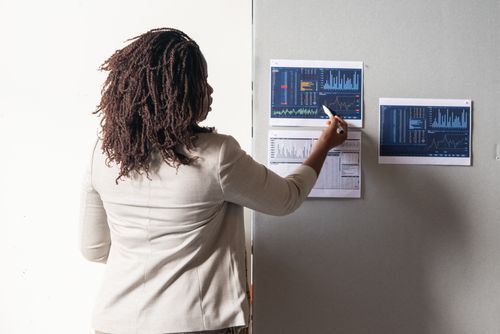 Free A businesswoman in a suit presenting financial data on charts during a meeting. Stock Photo